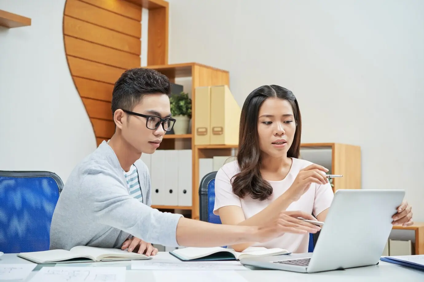 Junge Geschäftsleute arbeiten gemeinsam an einem Laptop.